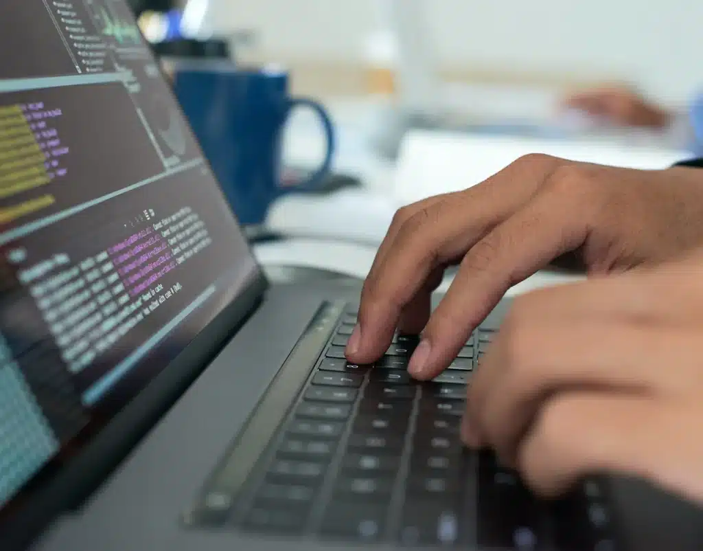 mains tapant sur un clavier d ordinateur affichant du code m